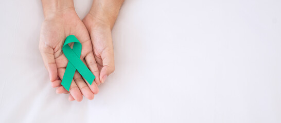 September Ovarian cancer Awareness month, Woman holding teal Ribbon color on blue background for supporting people living, and illness. Healthcare and world cancer day concepts