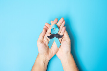 Fototapeta na wymiar November Prostate Cancer Awareness month, adult Man holding light Blue Ribbon with mustache for supporting people living and illness. Healthcare, International men, Father and World cancer day concept