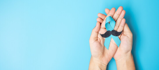 November Prostate Cancer Awareness month, adult Man holding light Blue Ribbon with mustache for...