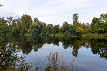 Calm river water reflecting country landscape in september evening light