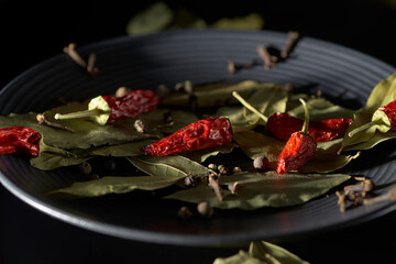 Bay leaves and red pepper on a dark plate