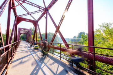 Motion blur bikers cross a bridge over the Boise River