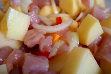 raw Turkey meat cut into pieces, onions, potatoes and red yellow sweet peppers close before baking in the oven . cooking at home