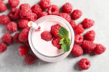 Yummy raspberry smoothie in jar and fresh berries on table, flat lay