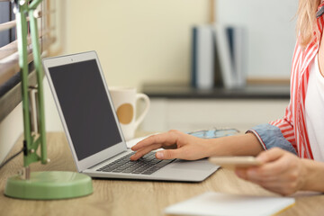 Young woman working on laptop at table, closeup