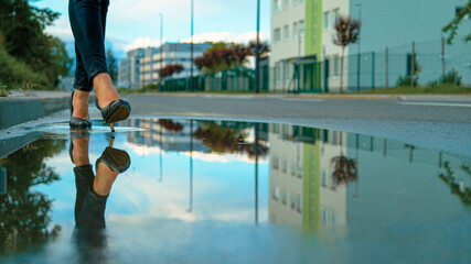 CLOSE UP Businesswoman in heels steps into a puddle on the side of an empty road