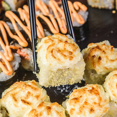 close up of chopsticks taking portion of sushi roll on the table restaurant