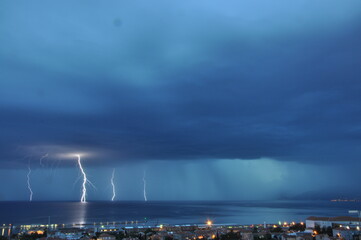 Naklejka na ściany i meble Thunderbolt severe weather on sea bolt strikes in the sea. Storm weather in Rijeka bay, Croatia.