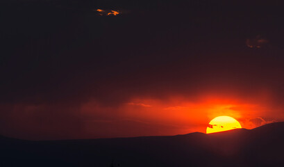 Obraz premium Sunset sky, big sun set over the mountains. 