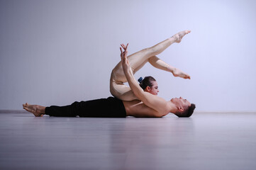 Acrobatic couple perform number on a white background. A duet of gymnasts rehearsing a performance...