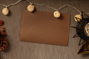 Cozy background with a brown sheet of paper, lights and a warm lamp, pine cone, with copyspace, mock up
