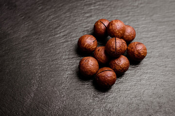 Macadamia nuts in their shells on an empty dark background