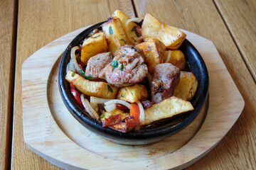 Meat in a frying pan, baked with vegetables and potatoes. Dish of Mediterranean cuisine. Restaurant shooting.