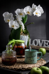 Turquoise mug with tea. Glass teapot with berry tea. Green apple. Still life on a dark table.