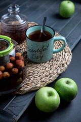 Turquoise mug with tea. Glass teapot with berry tea. Green apple. Still life on a dark table.