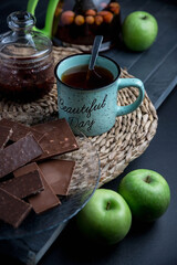 Turquoise mug with tea. Glass teapot with berry tea. Green apple. Still life on a dark table.