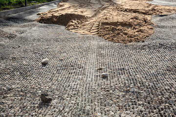 Stage of road surface construction. Aligns the sand layer over the geogrid.