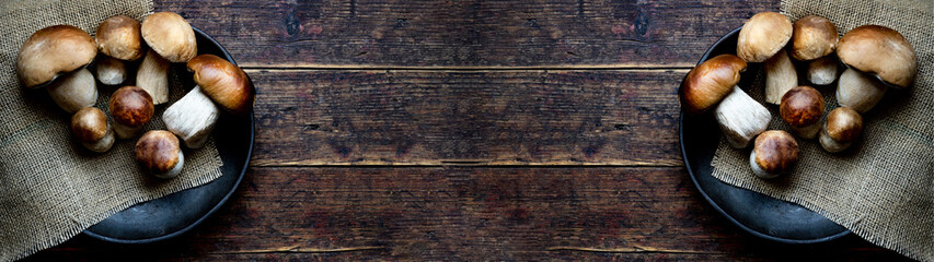 Fresh forest mushrooms /Boletus edulis (king bolete) / penny bun / cep / porcini in an old bowl / plate on the wooden dark brown table, top view background banner panorama