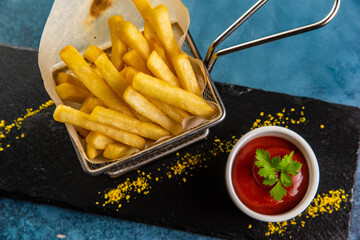 French fries in the basket with ketchup on blue table