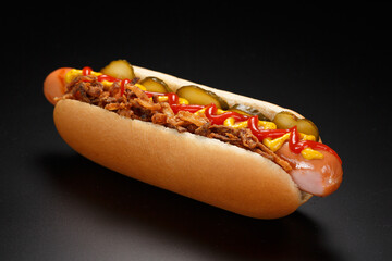 Danish hot dog with pickled cucumbers, fried onions and a hot dog with mustard, lettuce and jalapenos on a black background. - obrazy, fototapety, plakaty