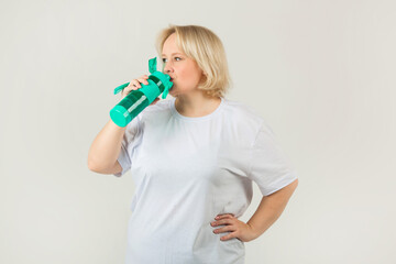 beautiful young plump woman in a white t-shirt on a white background with a shaker