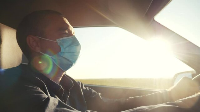 worker driver taxi wearing medical mask drives a car during the coronavirus period. delivery during the pandemic parcel concept. man wearing a mask driver protection against coronavirus