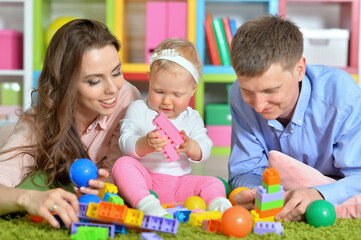 Fototapeta na wymiar Parents playing with adorable little daughter at playroom