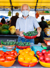 retired european man wearing medical mask protecting against virus selling vegetables in market