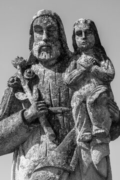 Saint Joseph with little Jesus Christ. Very ancient stone statue. White and black image.