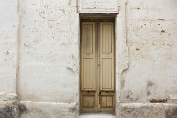 Typical Maltese yellow wooden old door on the limestone wall. Malta. Concept of traditional Maltese street view, vintage architecture.