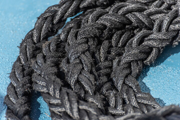 Thick, black rope on a blue ship deck.