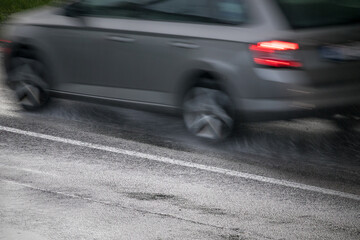 Fototapeta na wymiar silver car driving on a wet road in the rain