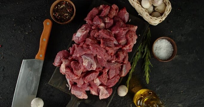 Pieces of beef on table with rosemary and garlic rotate. 