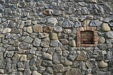 Antique wall of granite stones with a window