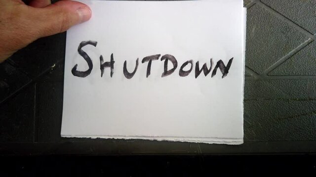 Several handwritten notes in black block capital letters on white square pieces of paper scrolling 2020, quarantine, shutdown, face mask, virus, pandemic, placed on top of table, directly above static