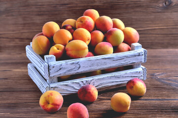 apricots in a white wooden box on a natural wooden brown background