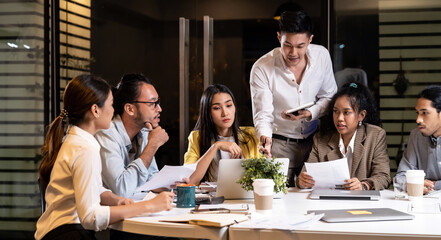 Working late, interracial asian business team brainstorm idea meeting.