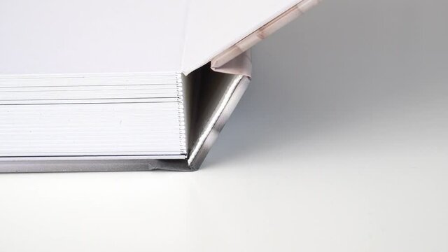 close up. spine of photo book with thick pages turns over on white table.