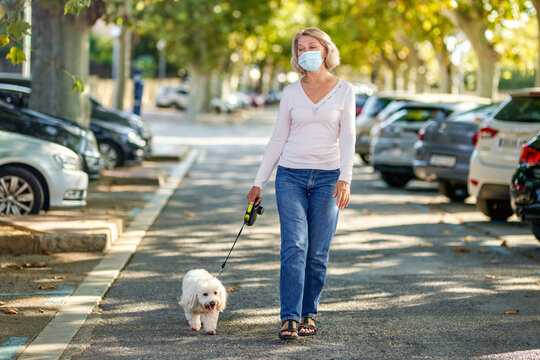 Mature Woman Walking With A Dog Outdoors An Antivirus Mask