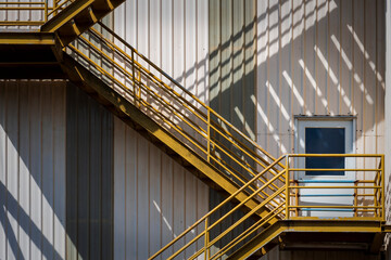 Sunlight and shadow on surface of fire escape outside of the old industrial building