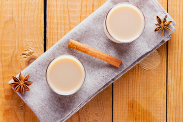 Herb tea with milk and spices. Homemade Indian Masala Chai Tea on wooden boards. Autumn drink in turkish tea cups