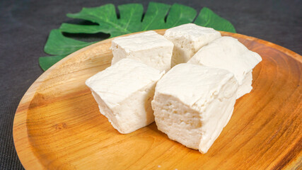 fresh tofu on wooden plate - vegan food concept