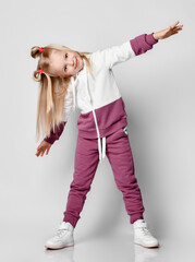 Little girl in sportswear having fun in the studio on a gray background.