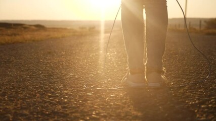 child jumping on a skipping rope close-up legs slow motion video silhouette. happy family kid dream concept. baby feet jumping on a skipping rope. girl in sneakers plays a skipping rope sunset - Powered by Adobe