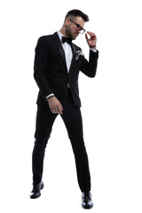 Fototapeta premium cool young businessman in tuxedo fixing sunglasses
