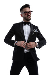 dramatic cool man looking to side and fixing tuxedo