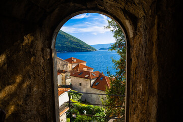 View of the wonderful sea city of Perast through the arch of the old cathedral, great postcard