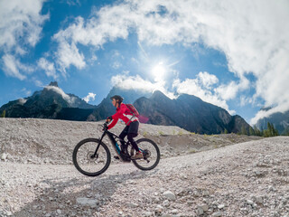 Fototapeta na wymiar pretty senior woman riding her electric mountainbike in the Innerfeld Valley in the Sexten Dolomites near village of Innichen , Tre cime National park, South Tirol, Italy 