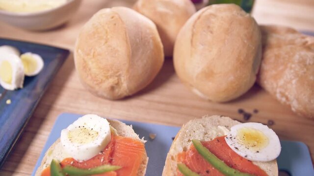 Person preparing egg and smoked salmon sandwich for breakfast. 