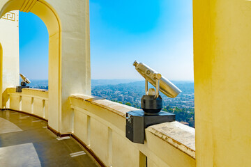 Unoccupied coin operated telescope binoculars on open balcony overlooking city landscape. Empty...